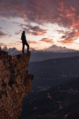 Adventurous man is standing on top of the mountain and enjoying the beautiful view. Taken on top of Cheam Peak in Chilliwack, East of Vancouver, BC, Canada. Colorful Sunset Sky Art Render
