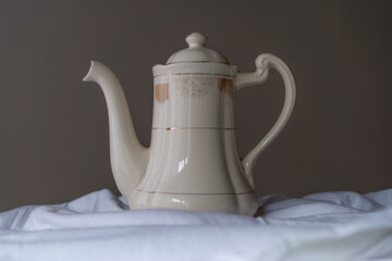 beautiful old tea pot or coffee maker. With a beige background on a white cloth.