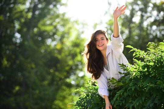 Friendly woman saying hello greetings on nature background in summer or spring park.