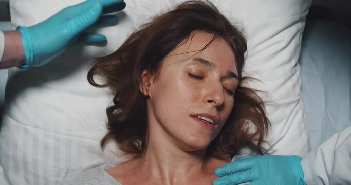 Top view of female patient suffering from high fever lying unconscious in hospital bed