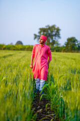 Naklejka na ściany i meble Young indian farmer walking at green wheat field