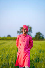 Young indian farmer walking at green wheat field