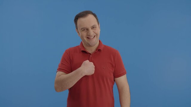 This is me! Confident young man pointing at himself.Proud, egoistic confident young man in red ti shirt, pointing at himself and looking arrogant. Indoor studio shot isolated on blue background.