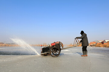 Farmers use electric saws to cut river ice in the wild.
