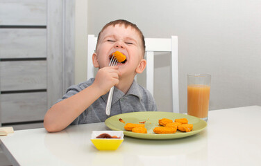 Pretty boy is happy to eat nuggets. The child at home eats junk food