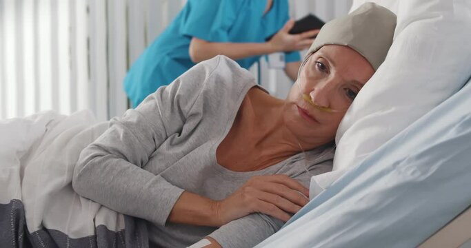Depressed and hopeless cancer patient woman wearing head scarf in hospital.