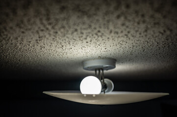 popcorn textured ceiling with LED bulb light fixture and glass cover