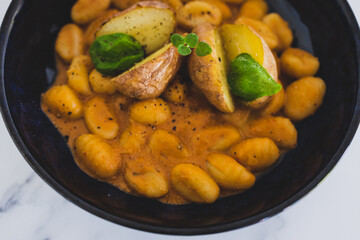 vegan gnocchi with dairy-free pumpkin sauce and roasted potatoes with basil