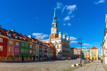Renaissance building of historic Poznan Town Hall surrounded by colorful townhouses in Market Square in sunny day, Poland