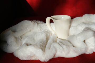 Morning coffee in bed. White cup on white fluffy plaid. Shadow and sunlight. At home. Lazy weekend