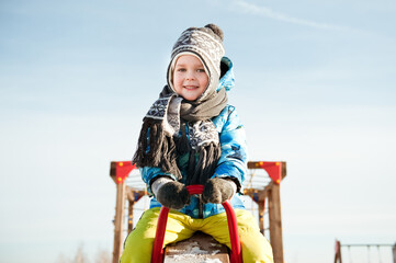 A cheerful child plays on the Playground on a winter day.