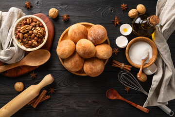 Fototapeta na wymiar cooked fresh buns for breakfast on wooden background among the ingredients, flat lay