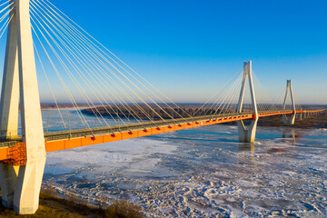 Aerial view of multispan cable-stayed Murom Bridge across ice covered Oka river on sunny winter day, Vladimir region, Russia.