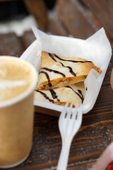 Street food and coffee on a wooden table in the street in winter