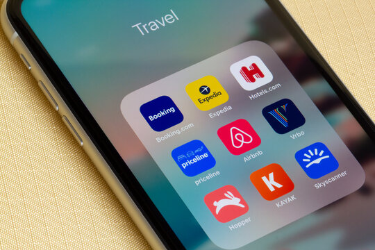 Portland, OR, USA - Feb 10, 2021: Assorted travel apps are seen on an iPhone on a lounge chair - Booking.com, Expedia, Hotels.com, Priceline, Airbnb, Vrbo, Hopper, KAYAK, and Skyscanner.