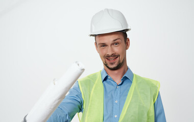 A man builder with a plan in the hands of a roll of paper white hard hat