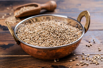 Hemp seeds in a copper bowl. Organic hemp seeds on wooden background