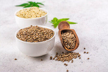 Organic hemp seeds and cannabis leaf on light background. Copy space