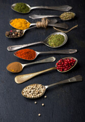 Various spices spoons on black table. Top view with copy space