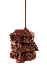 Porous chocolate pieces and chocolate syrup, isolated on white background. Black aerated chocolate.