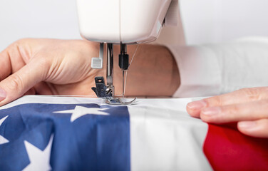 Male hands sewing american flag on sewing machine for us holiday