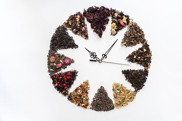 Different tea mixture with berries and flowers are lined in the form of a clock dial with arrows on...