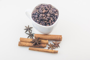 Coffee cup with beans, anise and cinnamon on white background.