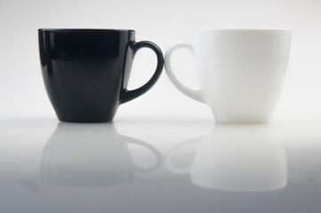 Mug mock up. Two ceramic mugs on white background. Blank coffee or tea mugs. Black cup and white cup. Copy space