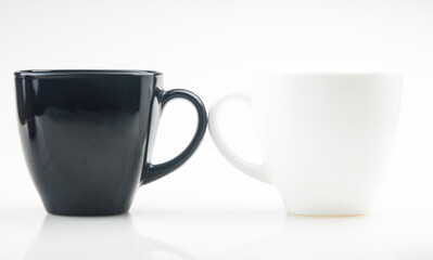 Mug mock up. Two ceramic mugs on white background. Blank coffee or tea mugs. Black cup and white cup. Copy space