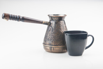 Black cup of coffee, copper cezve on white backgroun. Low key. Copy space