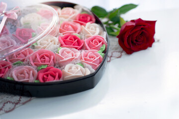Obraz na płótnie Canvas Rose shaped dessert in a heart shape gift box for Valentine's day, with rose flower near by on white background, presents for Valentine's day