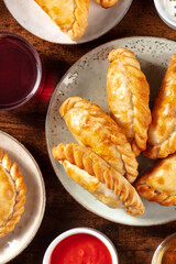 Empanadas with red wine and tomato sauce, overhead shot on a dark rustic wooden background