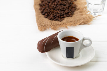 Cup of coffee and saucer with chocolate sweets on wooden table