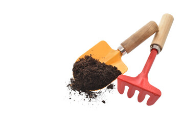 Yellow metal shovel with black soil or compost and red metal rake isolated on white