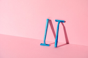 Blue disposable razors on pink paper background