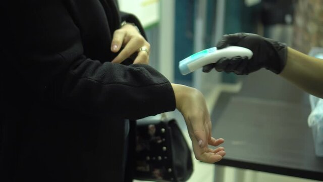 Mandatory measurement of a fever non-contact thermometer gun of all office workers. Happy woman with normal body temperature. Infrared portable device needed during an epidemic.