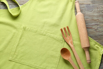 Clean apron and kitchen utensils on wooden background, closeup