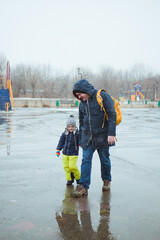 Father and son walk in the wet snow in the city Park.