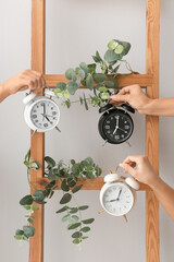 Female hands with alarm clocks on grey background