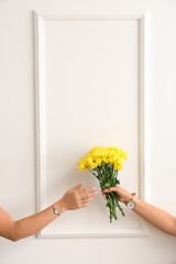 Female hands with wrist watches and flowers on light background