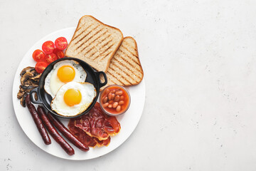 Traditional English breakfast with fried eggs in plate on light background