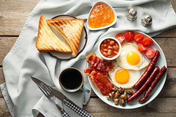 Traditional English breakfast with fried eggs on wooden background