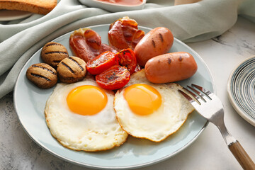 Traditional English breakfast with fried eggs on light background