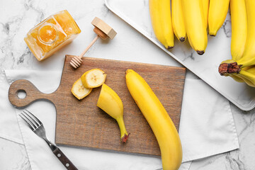 Wooden board with tasty bananas on light background © Pixel-Shot