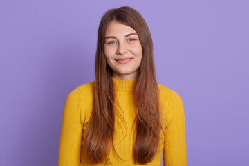 Obraz premium Portrait of young beautiful cute cheerful girl, looking at camera with charming smile, posing isolated over lilac background, wearing yellow sweater, good looking lady smiling, expresses positive.