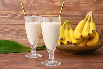 Glasses with tasty banana smoothie on wooden background