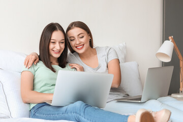 Young lesbian couple with laptops at home