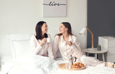 Young lesbian couple having breakfast in bed