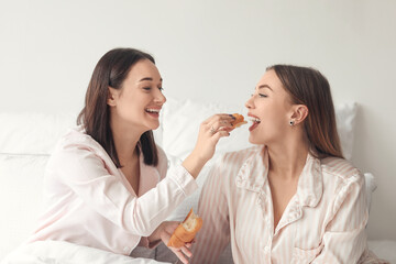 Obraz na płótnie Canvas Young lesbian couple having breakfast in bed