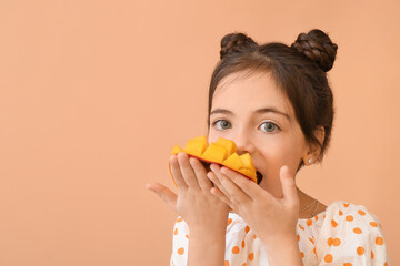 Cute little girl eating tasty mango on color background